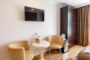 イスタンブールにあるクムル ホテルの椅子2脚、テーブル、テレビが備わる客室です。