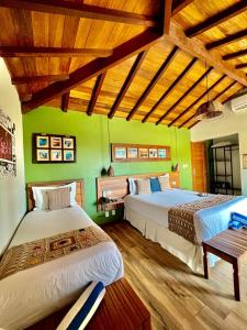Duas camas num quarto com paredes verdes e pisos em madeira em Pousada Villa Canaã em Búzios