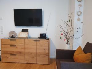 - un salon avec une commode en bois et une télévision à écran plat dans l'établissement Sepp, à Bad Tölz