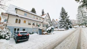 samochód zaparkowany przed domem w śniegu w obiekcie Hotel garni Am Hochwald w mieście Braunlage