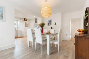 a dining room with a white table and white chairs at Delightful Family Getaway Cornwall in Mawnan Smith