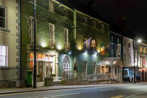 - un bâtiment vert dans une rue de la ville la nuit dans l'établissement Club House Hotel Kilkenny, à Kilkenny