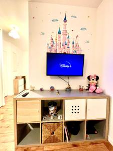 - une télévision dans une chambre ornée d'une fresque murale représentant le château de Dubaï dans l'établissement 5 Min from Disneyland cozy retreat, à Montévrain