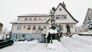 une maison enneigée avec un compteur de stationnement devant elle dans l'établissement Hotel garni Am Hochwald, à Braunlage