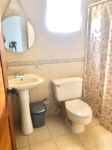 een badkamer met een toilet, een wastafel en een spiegel bij Apartamento en Pueblo Bavaro in Punta Cana
