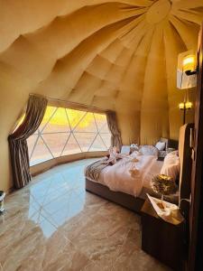 a bed in a room with a large window at Maraheb Luxury camp in Wadi Rum