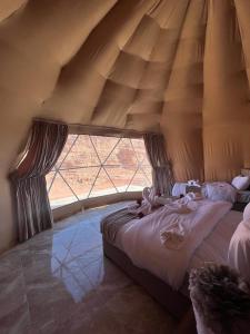 a bed in a room with a large window at Maraheb Luxury camp in Wadi Rum