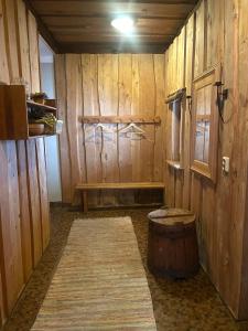 a room with a wooden wall with a barrel and a bench at Vecvanagi in Jaunmuiža