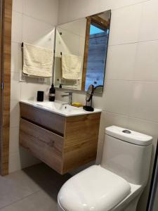 een badkamer met een toilet, een wastafel en een spiegel bij Estudio luminoso con balcón in Quito