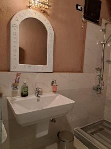 y baño con lavabo blanco y espejo. en Miskaa Nubian House, en Naj‘ Tinjār