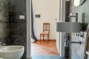 ein Badezimmer mit einem Waschbecken, einem WC und einem Stuhl in der Unterkunft Villa Orta - Agriturismo con cucina Vegan, Plant-based Farmhouse in Riotorto