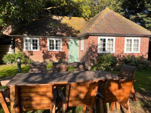 a wooden table with chairs in front of a house at Green Cottage in grounds of Grade II* Frognal Farmhouse in Sittingbourne