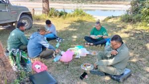 een groep mannen die in het gras eten bij Hotel Garden of Dreams in Sauraha