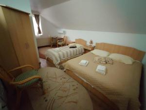 a small room with two beds and a chair at Pensiunea San in Arad