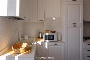 a kitchen with white cabinets and a microwave on a counter at BlueGreen in La Spezia