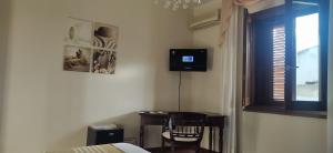 1 dormitorio con escritorio y TV en la pared en Golfo Asinara Suite guest house con vasca idromassaggio R4976, en Sorso