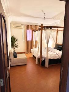 開羅的住宿－A lovely large master bedroom Maadi Degla，一间卧室配有一张天蓬床和一把椅子