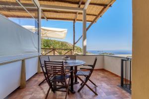 een tafel en stoelen op een balkon met uitzicht op de oceaan bij Villarena Relais in Nerano