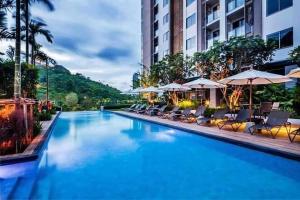 uma piscina com cadeiras e guarda-sóis num hotel em unixx seaview em Pattaya Sul
