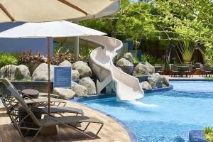 a slide in a pool with chairs and an umbrella at unixx seaview in Pattaya South