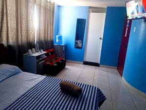 Schlafzimmer mit blauen Wänden, einem Bett und einem TV in der Unterkunft CASA COMPARTIDA in Chiclayo