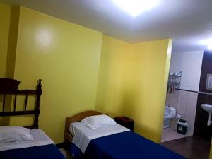 a bedroom with two beds and a yellow wall at CASA COMPARTIDA in Chiclayo