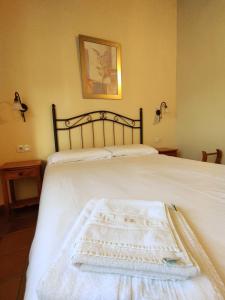 a bed with a white blanket on top of it at Casa Rural Puerta del Sol II de 2 habitaciones in Candelario