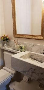 a bathroom with a sink and a toilet and a mirror at Ednamar Apartmentos Gramado Siena in Gramado