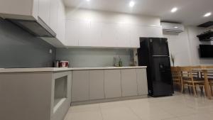 a kitchen with white cabinets and a black refrigerator at Meii House - Vinhome Ocean Park S201 in Hanoi