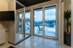 a living room with sliding glass doors with a view of the mountains at Apartament Widokowe Marzenie - blisko stoku, parking podziemny by SpaceApart in Karpacz