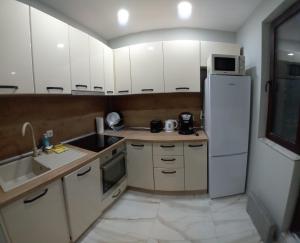 uma cozinha com armários brancos e um frigorífico branco em Витски em Ruse