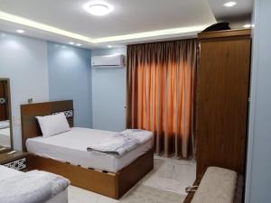 a bedroom with two beds and an orange curtain at The perfect stay in Cairo al muhandesin Nile luxury apartment in Cairo