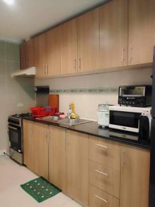 uma cozinha com armários de madeira, um micro-ondas e um lavatório em Boracay Apartment unit 5 em Boracay