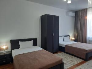 a hotel room with two beds and a cabinet at Апарт отель Welcome in Taldykorgan
