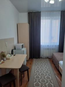 Habitación pequeña con cama, escritorio y mesa. en Апарт отель Welcome, en Taldykorgan