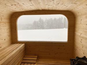 a window in a wooden sauna with snow covered trees at Apartamenty Arkadia Jaworzynka - Zapasieki in Jaworzynka
