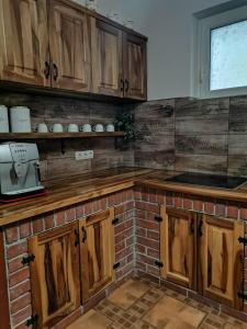 uma cozinha com armários de madeira e uma parede de tijolos em Dió vendégház em Praid