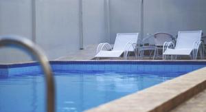 a pool with white chairs next to a swimming pool at Hotel Americas in Fortaleza