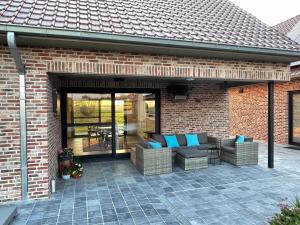 a patio with couches and chairs on a brick building at Landhuis Soetendaele in Wervik