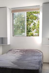 a bedroom with a large window in a white room at Apartamento Manizales Colombia in Manizales