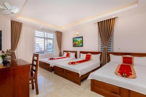 una camera d'albergo con 2 letti e una scrivania di ANH TUẤN HOTEL a Vung Tau
