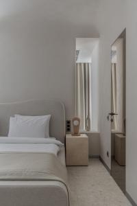 a white bedroom with a bed and a window at Sfumato Rooms in Odesa