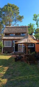 a house with a straw umbrella and a table at Los diablitos in Punta Del Diablo