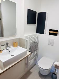 La salle de bains est pourvue d'un lavabo blanc et de toilettes. dans l'établissement Appartements 3 étoiles terrasse ou patio intra-muros, à Aigues-Mortes