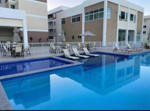 Una piscina con sillas y un edificio. en APARTAMENTO EM ILHÉUS - PRAIA DOS MILIONÁRIOS - VOG ATLÂNTICO - Pé na Areia, en Ilhéus