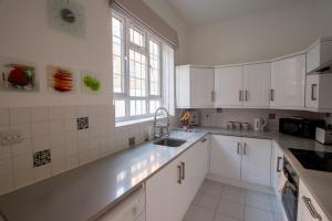 a kitchen with white cabinets and a sink and a window at Mayfair Town House in London