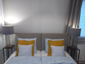 een slaapkamer met een bed met gele kussens en 2 lampen bij Apartament Łąkoszyn Kutno in Kutno