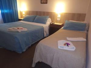 two beds in a hotel room with towels on them at Hotel PerlaMar in Mar del Plata