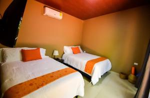 two beds in a room with orange and white at Cabaña Villa de Ada in Gracias