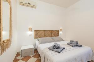 - une chambre blanche avec un lit et des serviettes dans l'établissement Maestrale a pochi passi dal mare, à Santa Maria Navarrese